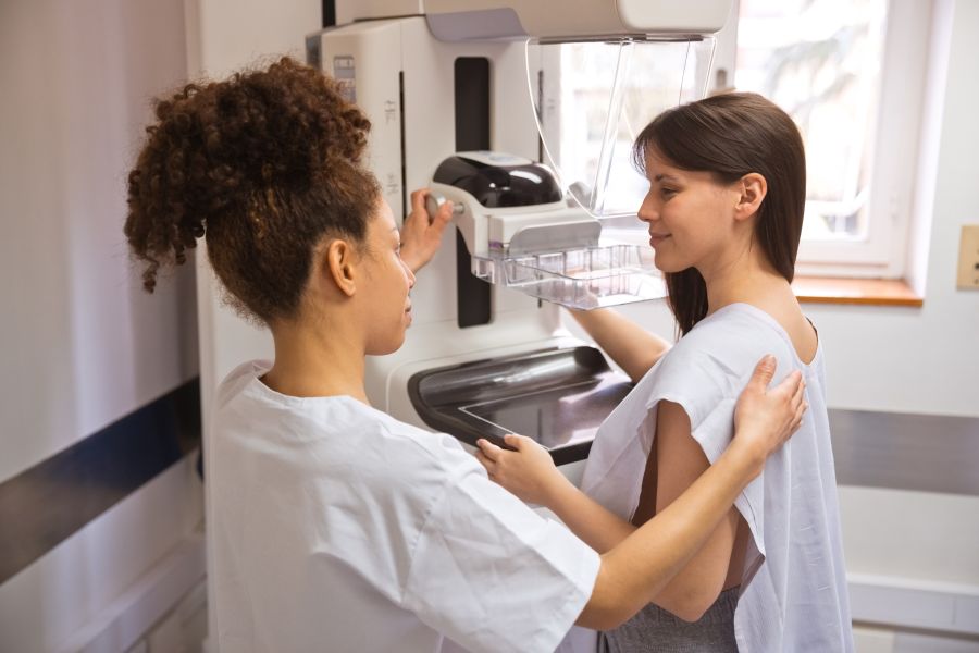 Female doctor talking to patient during Mammography test in examination room
