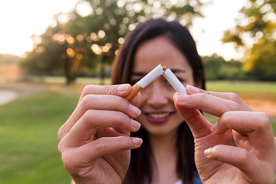 Young woman breaks cigarette in half