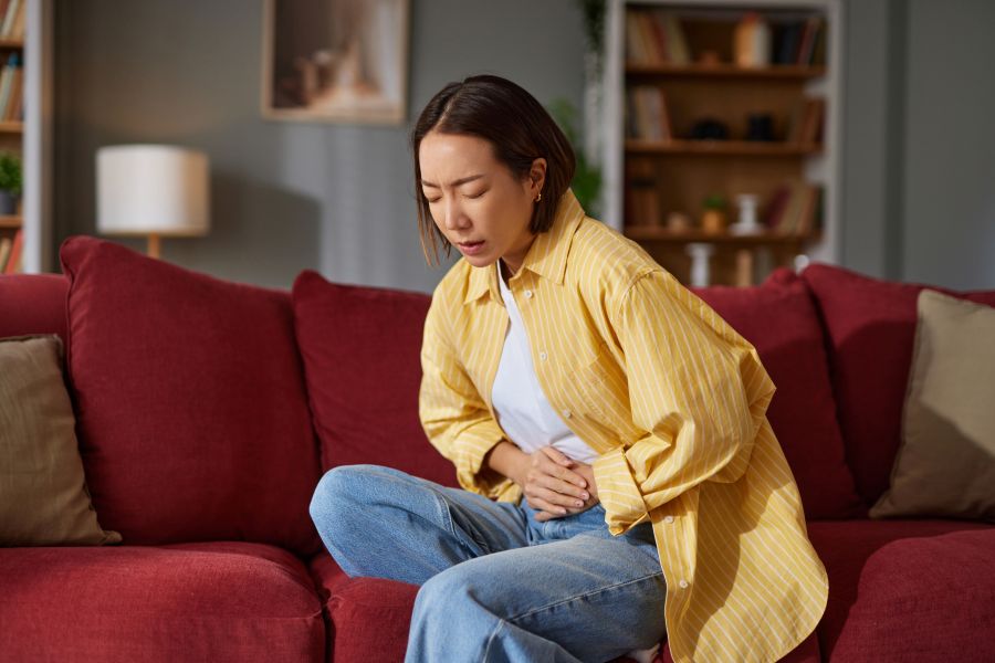 Young asian woman experiencing stomach pain at home
